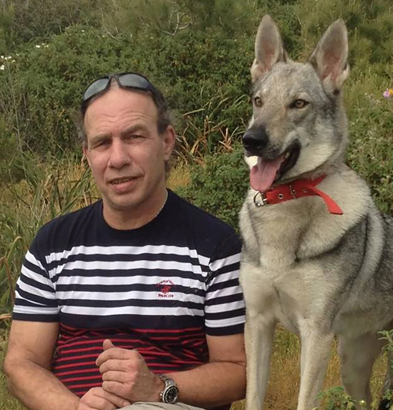 Portrait of artist Miki Karni with his dog outdoors.